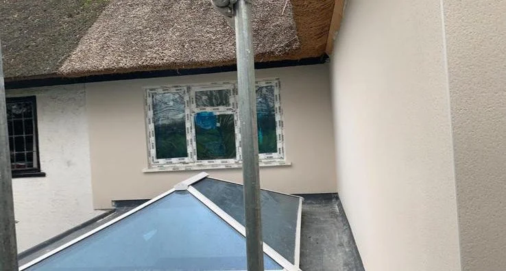 Exterior rendering and renovation work on property with thatched roof in Surrey.