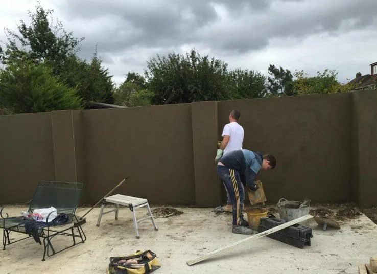 Professional plasterers preparing rendering materials during exterior wall project in Guildford Surrey.